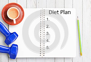 Top view of diet plan paper,pencil,cup of coffee and blue dumbbell