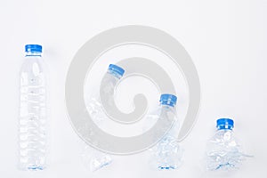 Top view of different empty plastic water bottles from full to crushed on white background. Recycle, World Environment Day and Eco