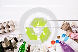 Top view of Different garbage materials with recycling symbol on white wooden table background. Recycle, World Environment Day and