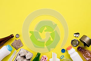 Top view of Different garbage materials with recycling symbol on yellow background. Recycle, World Environment Day and Eco concept