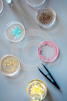 Top view of different glitter samples in petri dishes over a lab table background