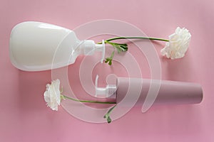 Top view of different hygienic/cosmetic products and flowers on fresh pink background. Wellness beauty treatment