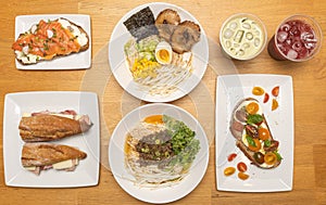 Top view of different meals with ramen, lemonades, and sandwiches on the kitchen table photo