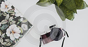 Top view of a digital camera near a beautiful album isolated on white background