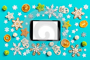 Top view of digital tablet on blue background with New Year toys and decorations. Christmas time concept