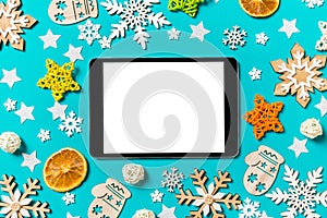 Top view of digital tablet on blue background with New Year toys and decorations. Christmas time concept