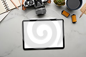 Top view of digital tablet with white screen, camera, coffee cup ans notebook on marble background.