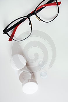 Top view of dioptric red-black glasses white cover for contact lenses and lenses on a white background. Concept of medicare.