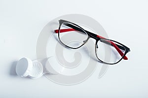 Top view of dioptric red-black glasses white cover for contact lenses and lenses on a white background. Concept of medicare.