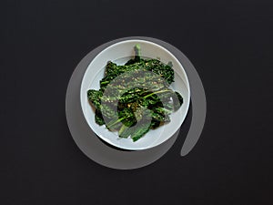 Top view of a dish of cooked kale with seasame seeds and ail photo