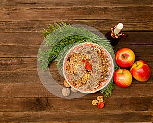 Top view of a dish of traditional Christmas dish Slavs - kutia. Wooden background spruce branch, apples