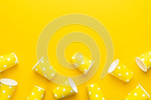 Top view of disposable paper cups on yellow background with copy space