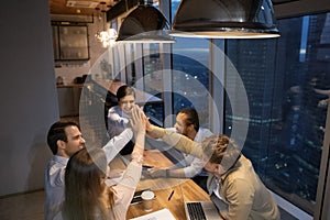 Top view diverse employees giving high five at late meeting