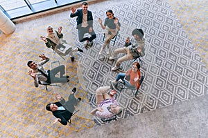 Top view of a diverse group of young business entrepreneurs gathered in a circle for a meeting, discussing corporate