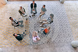 Top view of a diverse group of young business entrepreneurs gathered in a circle for a meeting, discussing corporate
