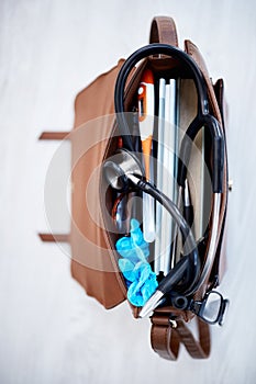 Top view, doctor bag and clinic with stethoscope, books and glasses on desk for job in medical industry. Doctors, nurse