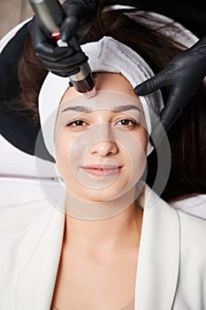 Woman receiving radiofrequency treatment in beauty salon. photo