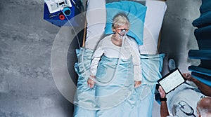 Top view of doctor and covid-19 patient with oxygen mask in bed in hospital, coronavirus concept.