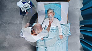 Top view of doctor and covid-19 patient with oxygen mask in bed in hospital, coronavirus concept.