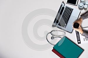 Top view of doctor desk table with stethoscope, coffee, Medical gown and notebook with pen