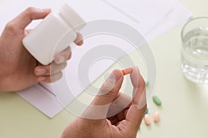 Top view of a doctor`s hand writing a prescription. A pill bottl