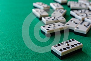Top view of dominoes, the six double focused, the rest out of focus, on horizontal green mat