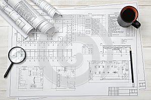 Top view of draftsman's workplace with plan, magnifier, pencil, mug coffee and rolled drafts photo