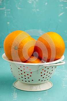 Top view of drainer with oranges, selective focus, on table and blue background, in vertical