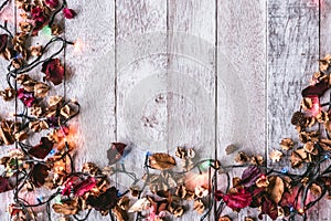 Top view of Dried flowers with Christmas lights on wooden table background. Free space for your text.