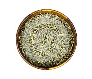 Top view of dried rosemary branches, twigs and leaves in a round wooden bowl isolated on white background.