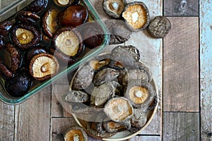 Top view Dried shiitake mushrooms soak in water and on wooden plate