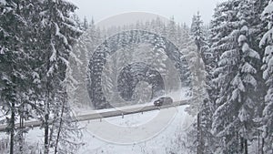 Top view from a drone of a car driving on a snowy icy road