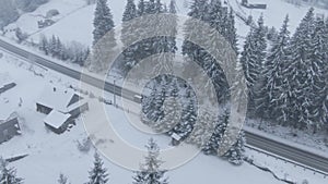 Top view from a drone of a car driving on a snowy icy road