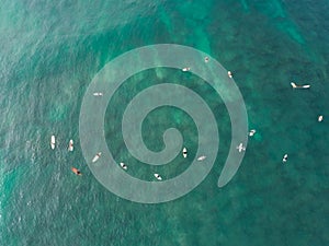 Top view from drone of many surfers waiting to catch next wave