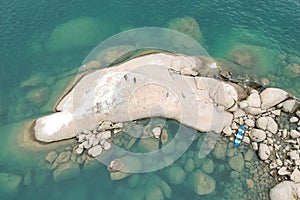 Top view drone shot of a stoney cliff of a coastline with two people