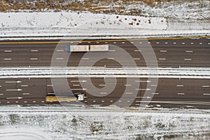 Top view from drone to winter asphalt highway or motorway road in countryside with car truck traffic driving fast