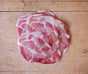 Top view of dry coppa on an old wood cutting board photo