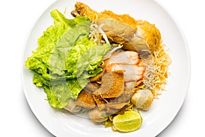 Top view of dry egg noodle topping with fried chicken drumstick, bean sprout, red pork, crispy wonton, lemon grass and vegetable