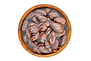 Top view of dry roasted cacao nibs in wooden bowl
