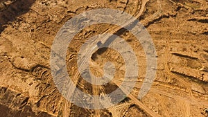 Top view of dusty sandy dirt road with wheels tracks and driving red truck. Scene. Truck moving and leaving a dusty