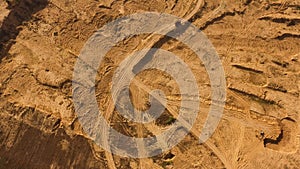 Top view of dusty sandy dirt road with wheels tracks and driving red truck. Scene. Truck moving and leaving a dusty