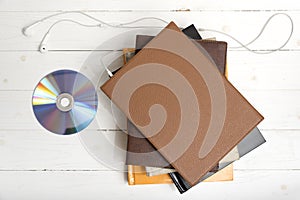 Top view of earphone with stack of book and dvd disc