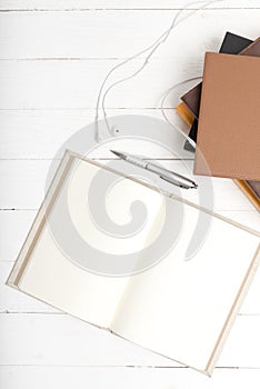 Top view of earphone stack of book and open notebook