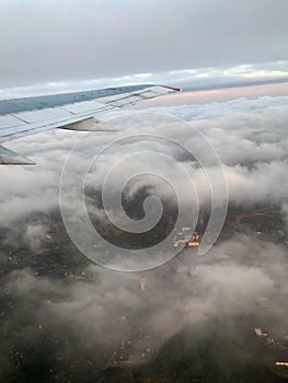 Top view of the earth from the porthole, the windows of the aircraft on the wing with engines, turbines and white fluffy, rain clo