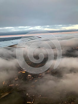 Top view of the earth from the porthole, the windows of the aircraft on the wing with engines, turbines and white fluffy, rain clo