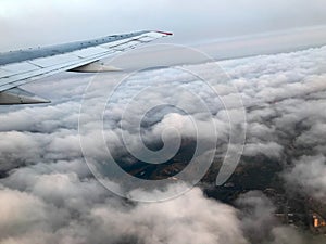 Top view of the earth from the porthole, the windows of the aircraft on the wing with engines, turbines and white fluffy, rain clo