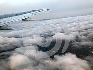 Top view of the earth from the porthole, the windows of the aircraft on the wing with engines, turbines and white fluffy, rain clo