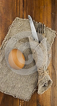 Easter background. Table setting for the holiday of Easter in a rustic style, burlap napkin, eggs, fork and knife on a wooden