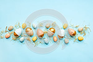 Top view of easter eggs colored with golden paint and differen colors. Blue background. Copy space