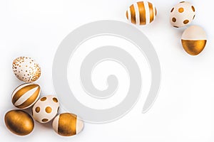 Top view of easter eggs colored with golden paint in differen patterns. Various striped and dotted designs. White background. Copy